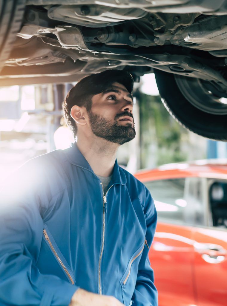 Auto Mechanic looking underneath a vehicle during an inspection - Book Your MOT in Liverpool